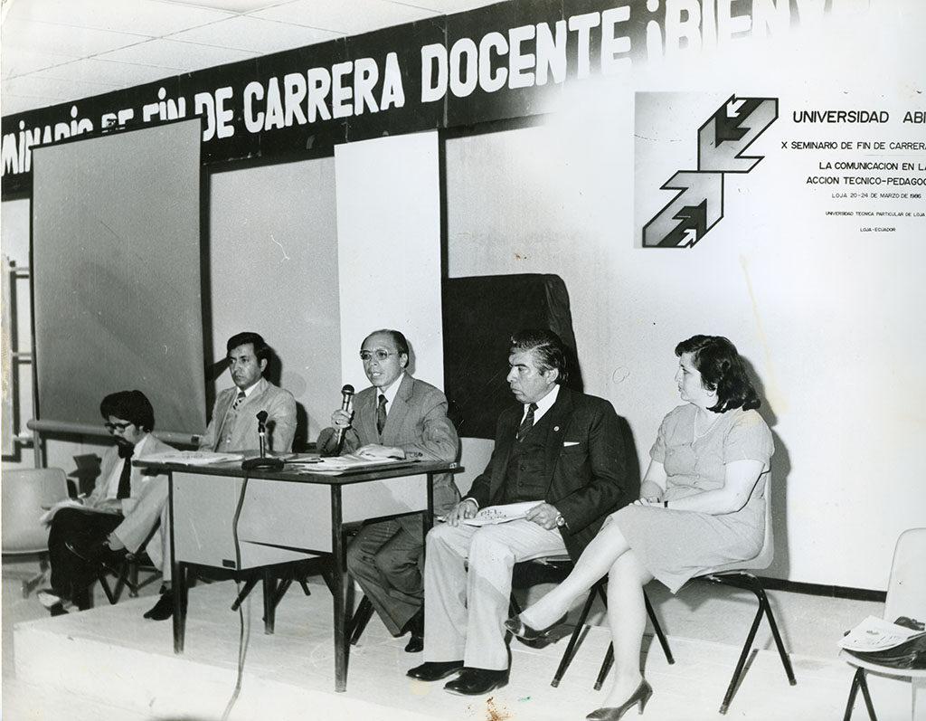 Foto a blanco y negro de un grupo de docentes en un auditorio de la universidad.