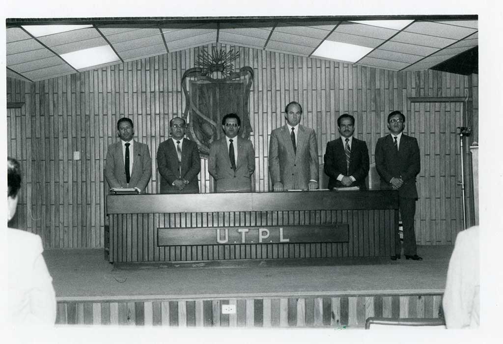Foto a blanco y negro de un grupo de autoridades de la UTPL que se encuentran en el aula magna.