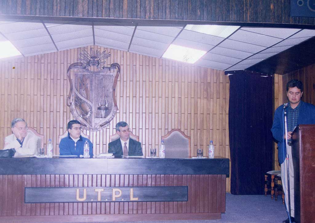 Foto a color de un grupo de autoridades dentro del aula magna de la UTPL.